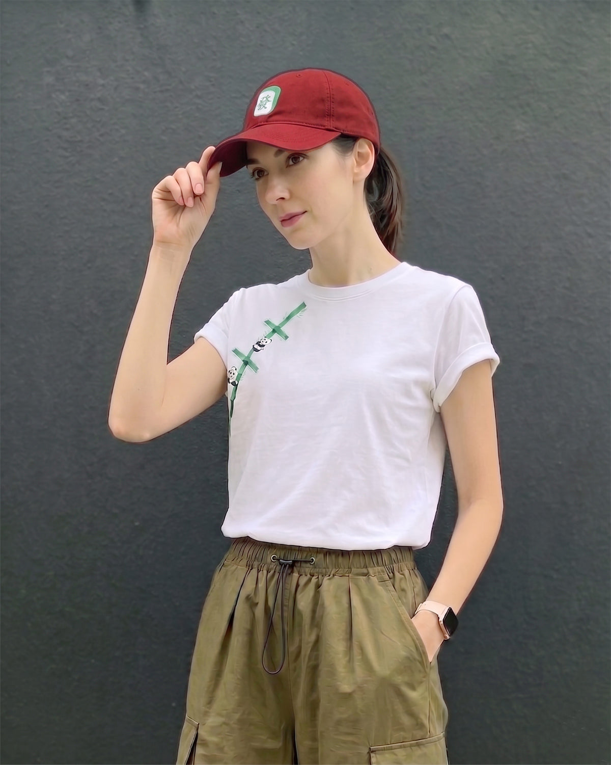 Person wearing a red cap and white t-shirt with green design against a dark background