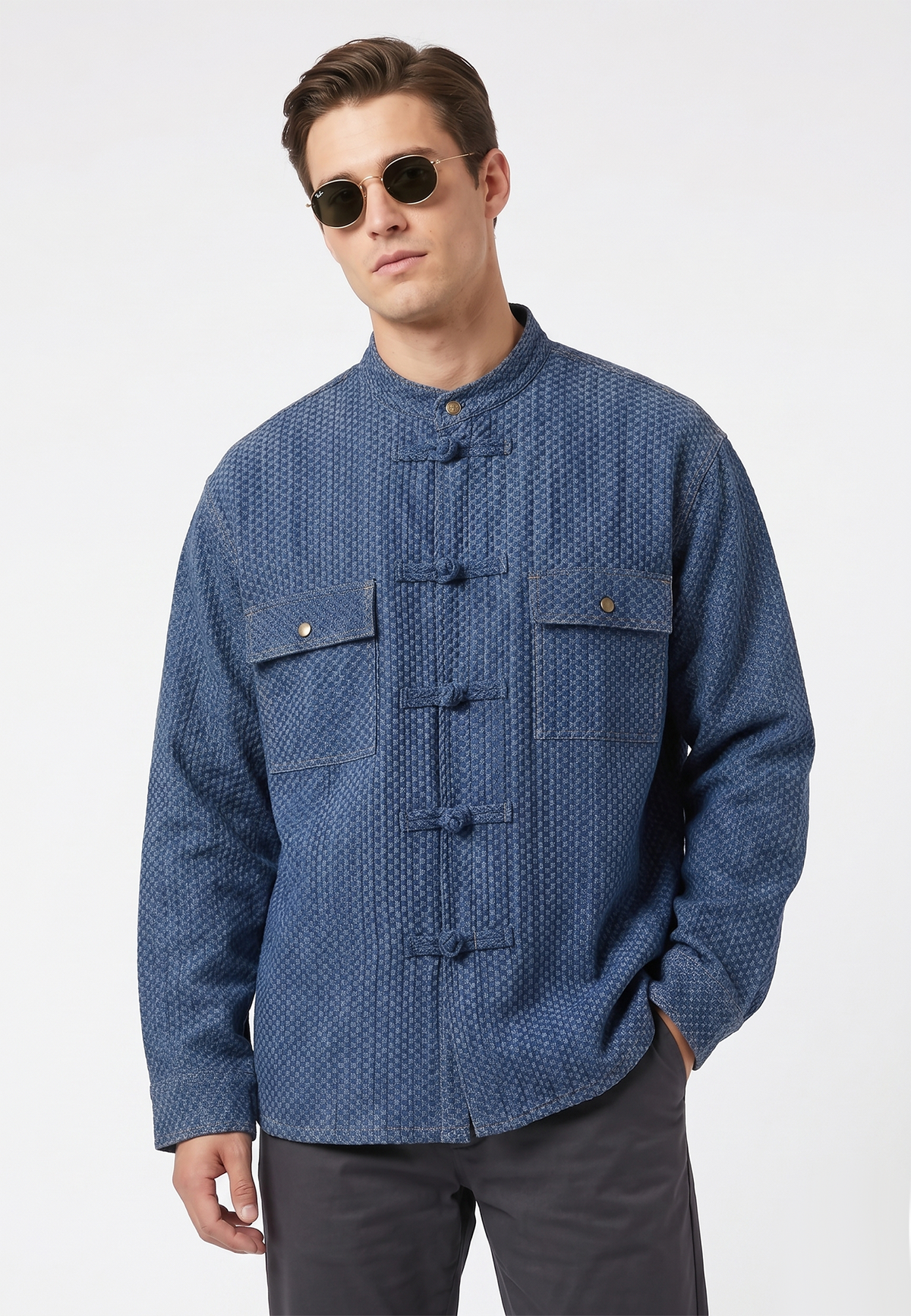 Man wearing a blue patterned shirt with button details on a white background