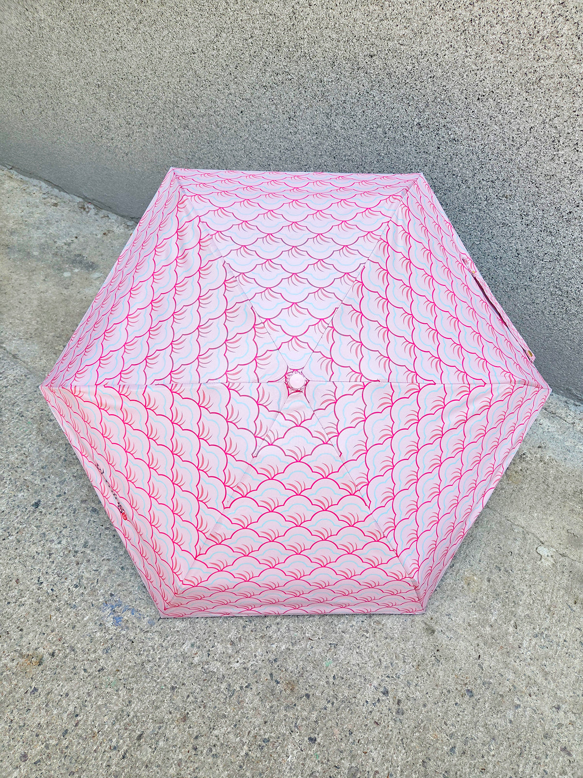 Pink textured umbrella on a concrete surface