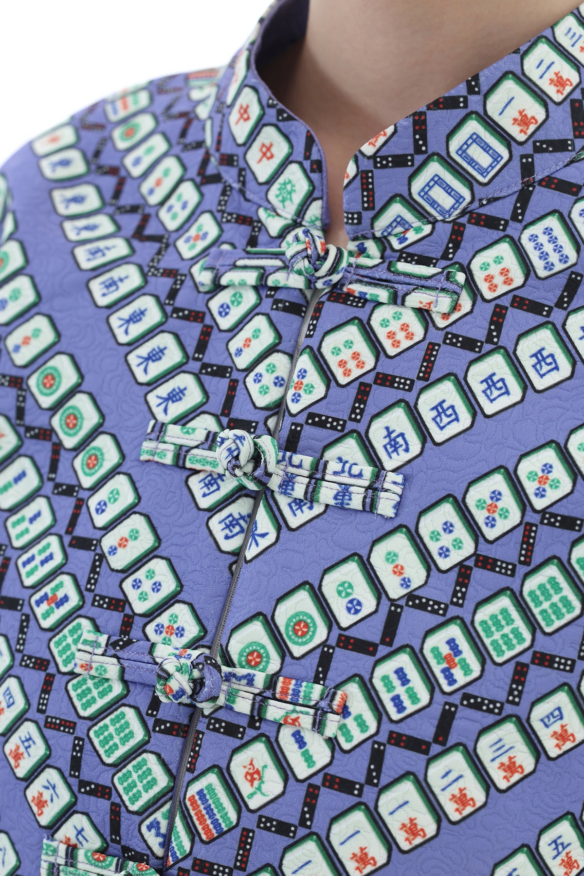 Close-up of a person wearing a lavender-purple traditional Chinese-style top with an all-over mahjong tile print and matching front ties.